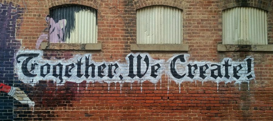 Backstein-Wand mit Graffiti "Together We Create!"